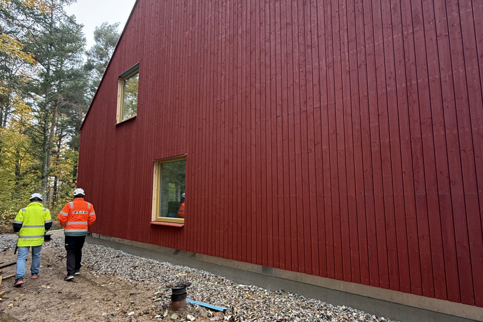 Två män går bredvid ett nybyggt hus.