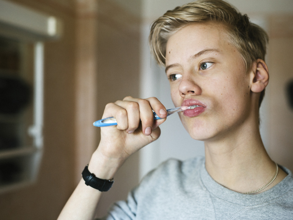 En tonårspojke borstar tänderna.