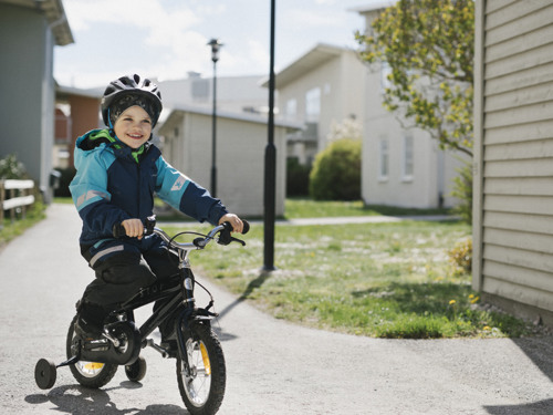 En pojke på en cykel i ett bostadsområde.