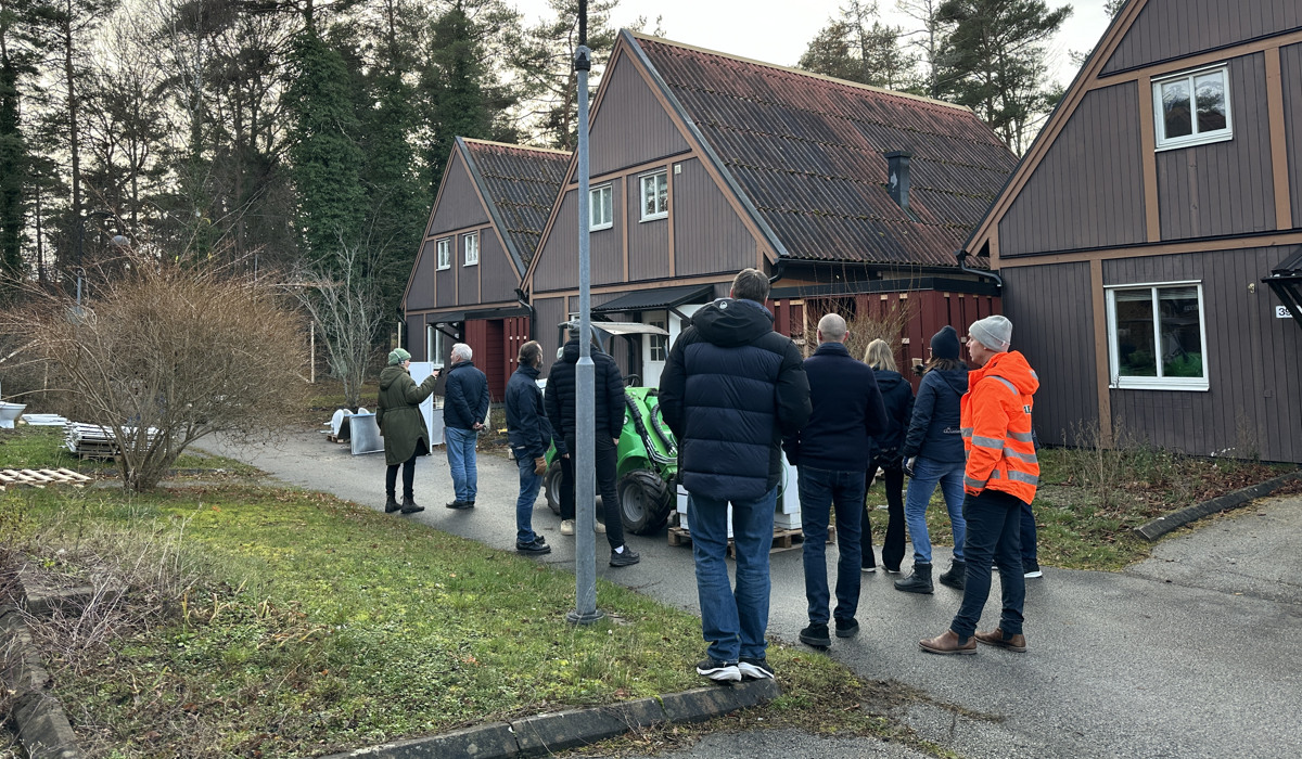 Kvarteret Riggen i Visby. Det är höst. Flera människor rör sig mot trähusen.